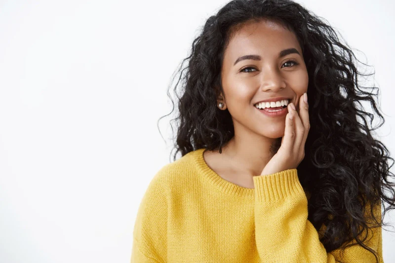 Smiling woman in a yellow sweater, an editorial portrait from Modern Touch Dental's previous website.